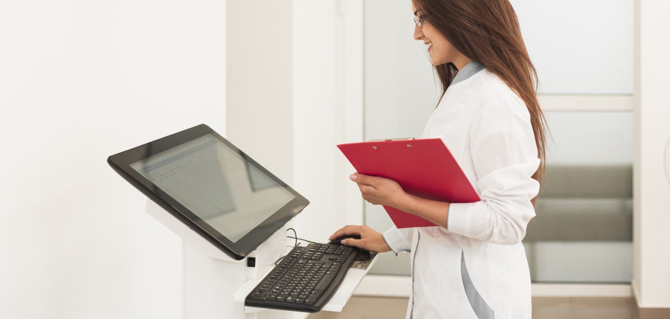 doctor-holding-clipboard-working-computer