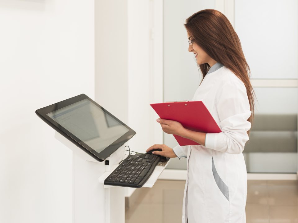 doctor-holding-clipboard-working-computer